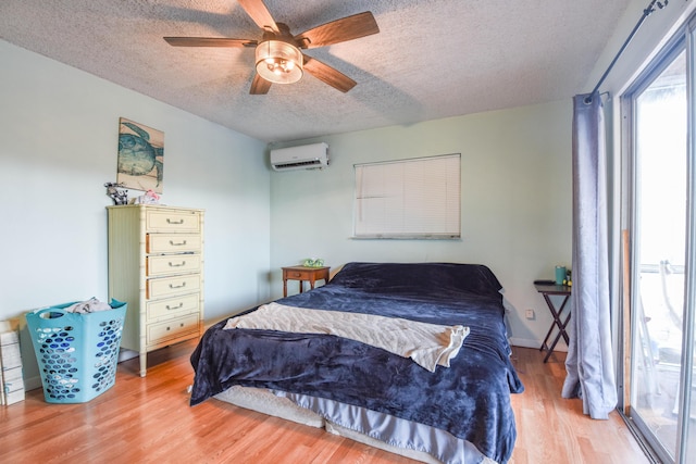 bedroom featuring hardwood / wood-style flooring, ceiling fan, a wall mounted AC, and a textured ceiling