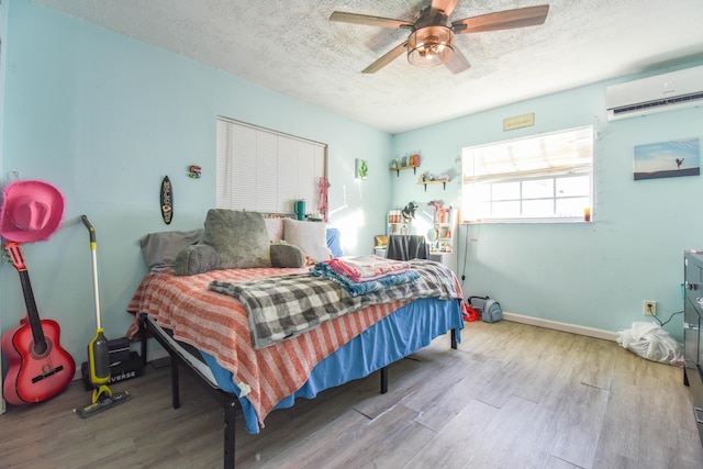 bedroom featuring a textured ceiling, a wall unit AC, and light wood-type flooring