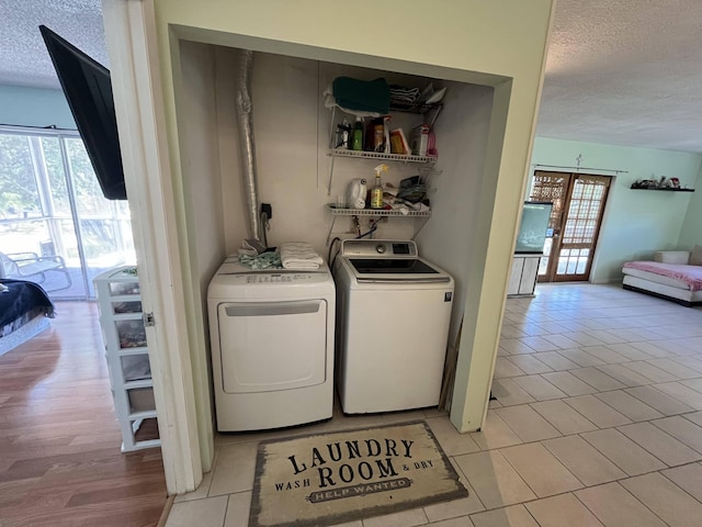 laundry area with washer and dryer, light tile patterned floors, and a textured ceiling