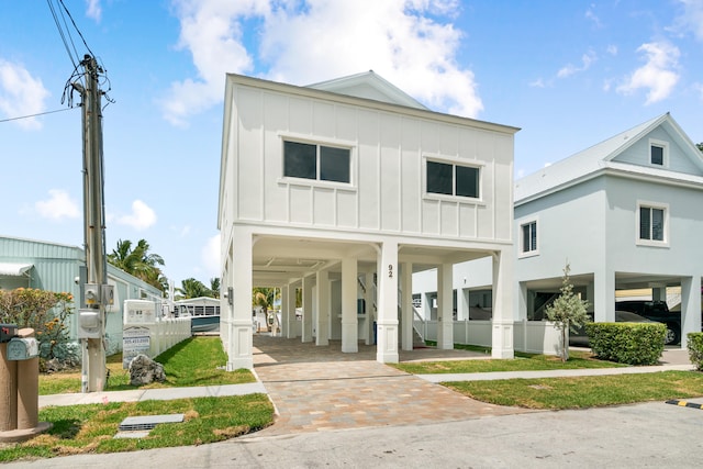 coastal inspired home with a carport, board and batten siding, and driveway