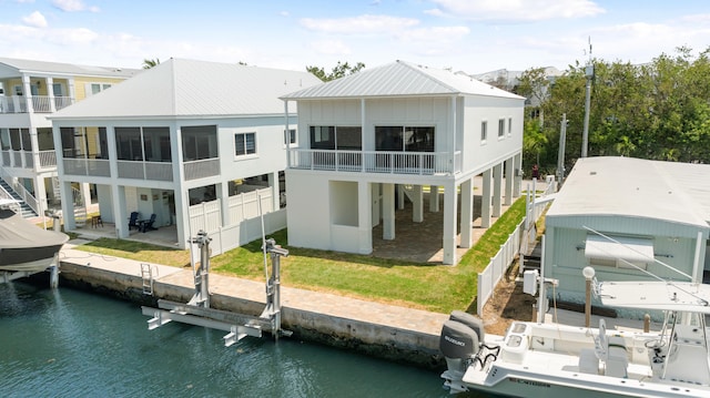rear view of property featuring boat lift, a water view, a sunroom, and a patio