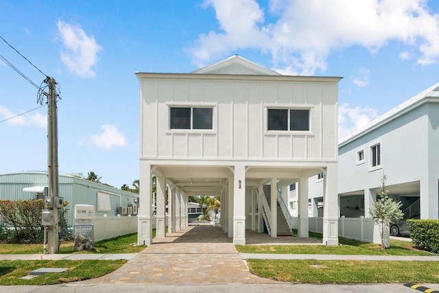 beach home with board and batten siding, a carport, stairs, and fence
