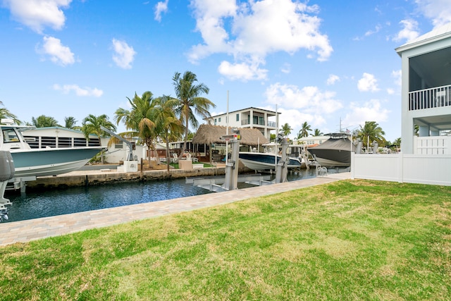 dock featuring boat lift, a yard, and a water view