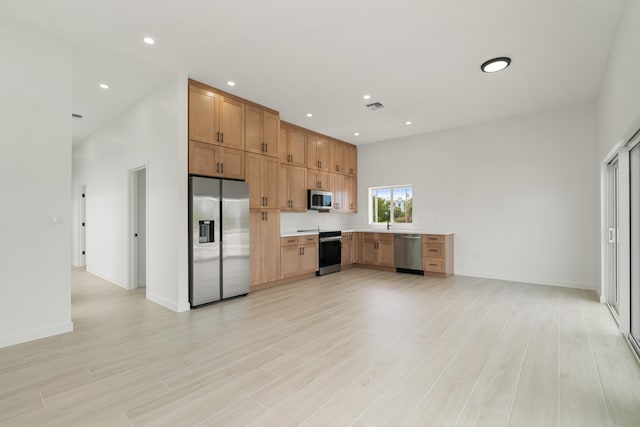 kitchen featuring appliances with stainless steel finishes, light countertops, light wood-style flooring, recessed lighting, and baseboards