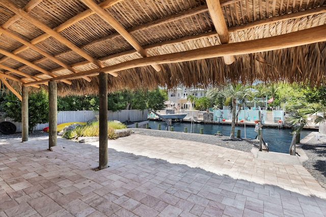 view of patio with boat lift, a boat dock, a water view, and fence