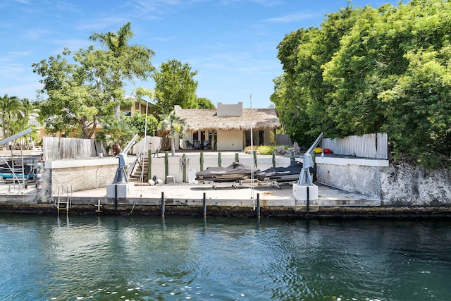 dock area featuring a water view, stairway, fence, and a patio