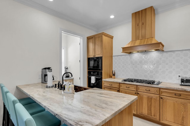 kitchen featuring light stone counters, crown molding, a sink, premium range hood, and black appliances