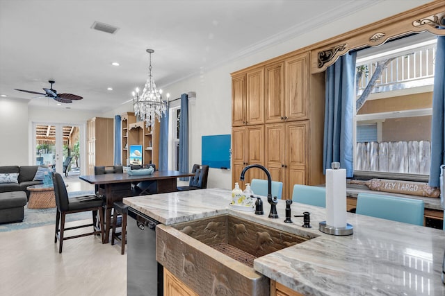 kitchen featuring light stone counters, ornamental molding, open floor plan, a sink, and dishwasher