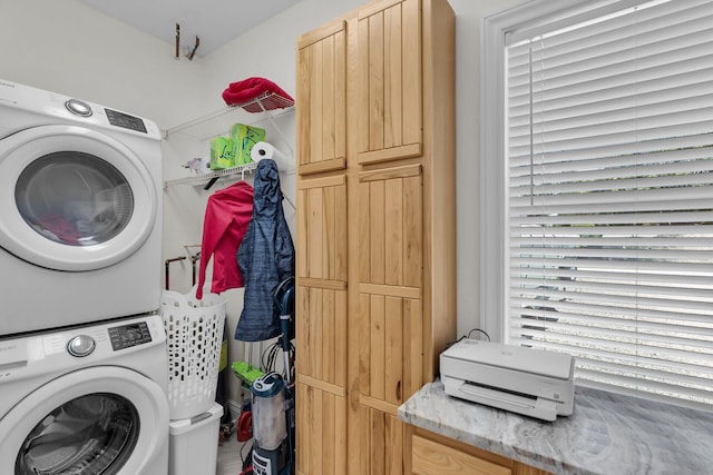 washroom with stacked washer and dryer and cabinet space