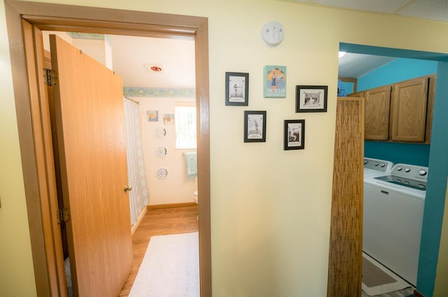 hall with light hardwood / wood-style floors and washing machine and clothes dryer