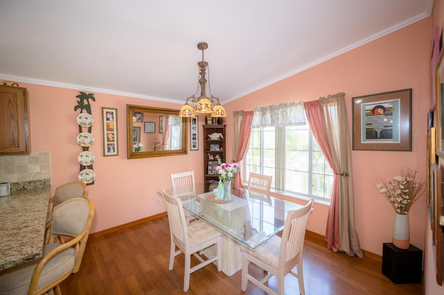 dining area with crown molding, vaulted ceiling, and hardwood / wood-style floors