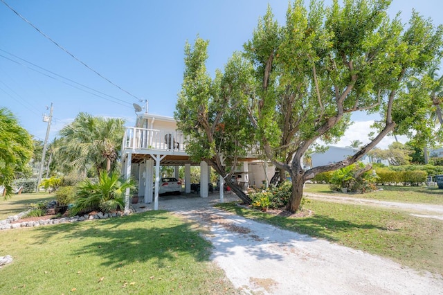 raised beach house with a front lawn and a carport