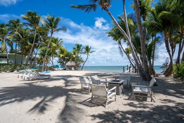 view of patio / terrace featuring a water view, a beach view, and a fire pit