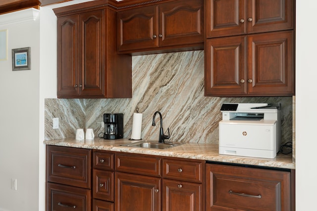 kitchen with tasteful backsplash, light stone countertops, and sink