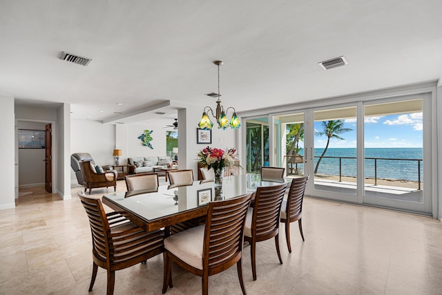 dining room featuring an inviting chandelier and a water view