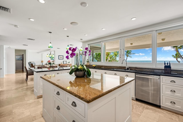 kitchen with sink, stainless steel dishwasher, a center island, and dark stone counters