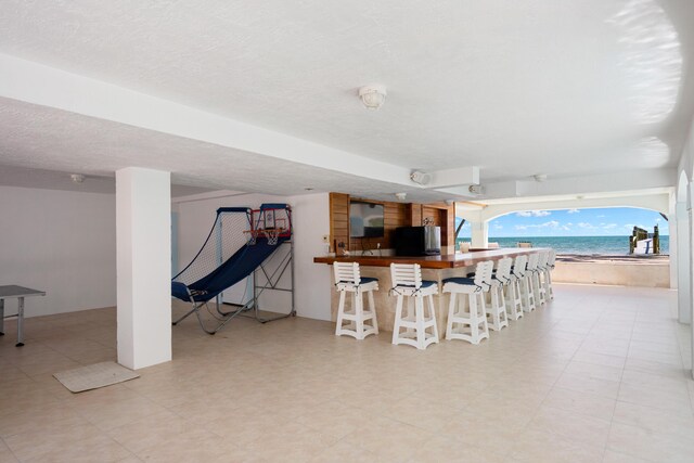 interior space with a water view, exterior bar, and a beach view