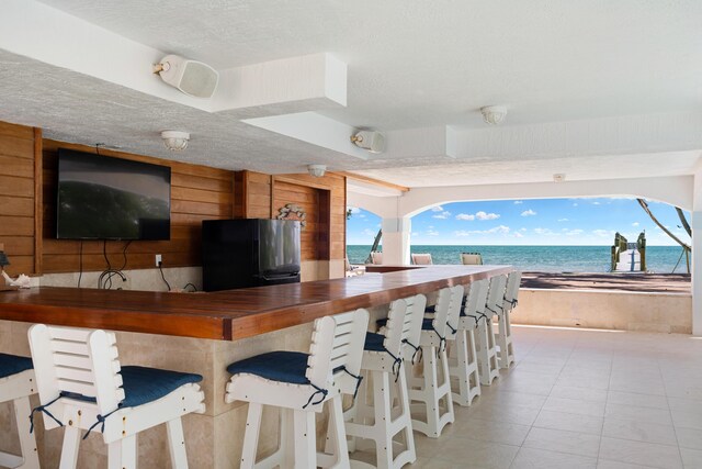 kitchen featuring black refrigerator, a water view, wooden counters, and a textured ceiling