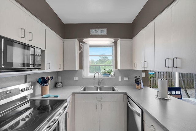 kitchen with sink, backsplash, white cabinets, and appliances with stainless steel finishes