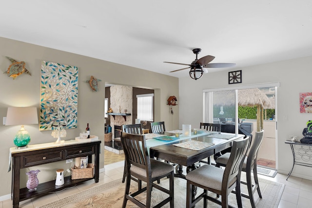 dining area with ceiling fan, light tile patterned floors, and a fireplace