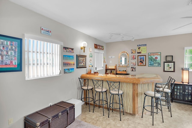 kitchen with rail lighting, a breakfast bar area, kitchen peninsula, and plenty of natural light