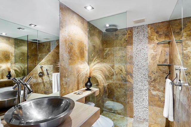 full bath featuring a sink, visible vents, tile walls, and walk in shower