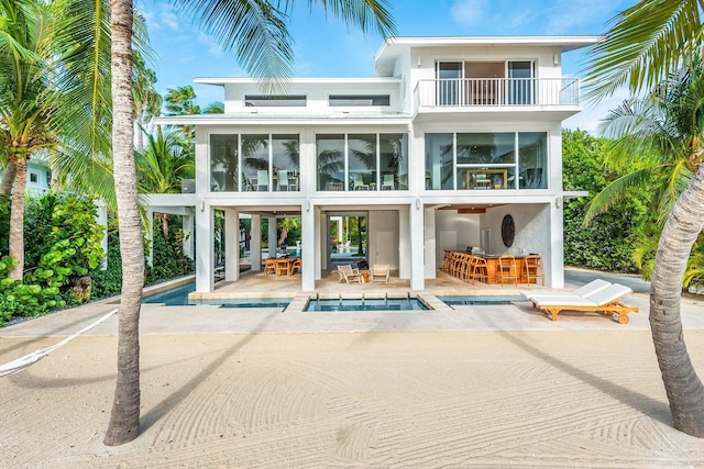 back of property featuring a patio area, stucco siding, a balcony, and a sunroom