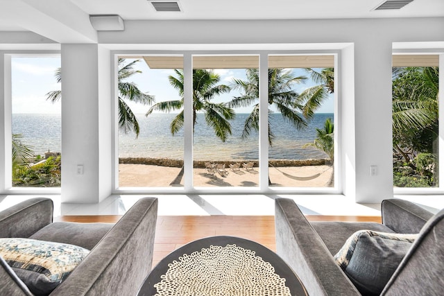 sitting room with hardwood / wood-style floors, a healthy amount of sunlight, and a water view