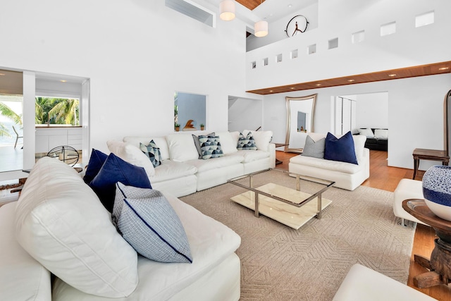 living area with recessed lighting, wood finished floors, visible vents, and a towering ceiling