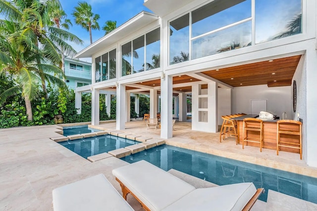 view of swimming pool with outdoor dry bar, a pool with connected hot tub, and a patio