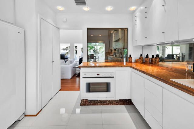 kitchen featuring white appliances, white cabinets, dark stone countertops, and visible vents