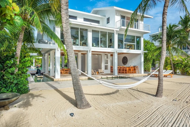 back of property featuring a balcony, a patio area, and stucco siding