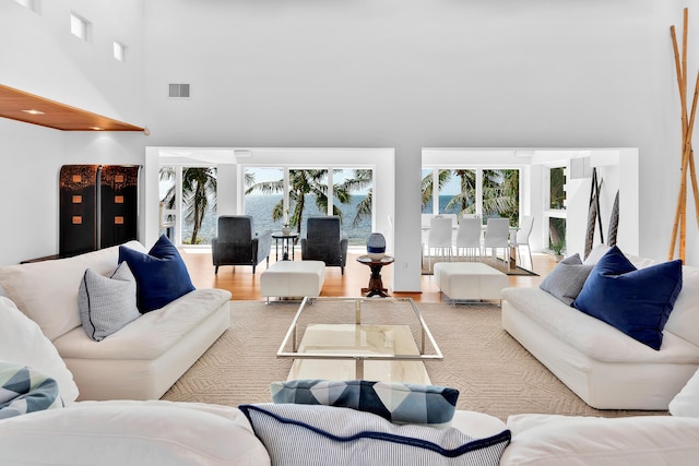 living area with a high ceiling, wood finished floors, and visible vents