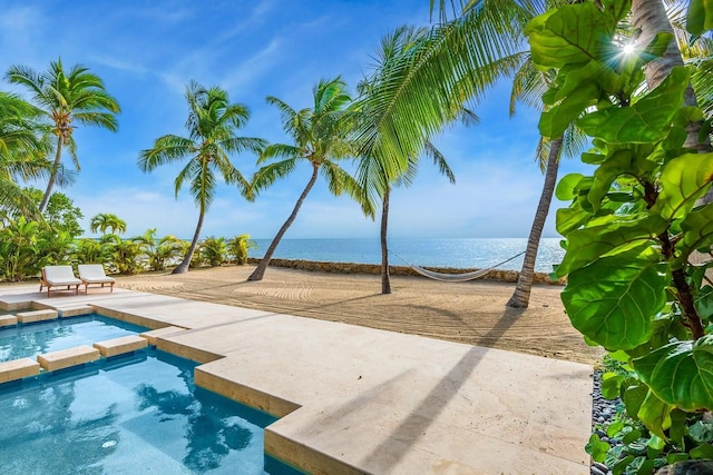 view of swimming pool with a patio area, a water view, and a pool with connected hot tub