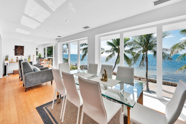 dining space featuring a water view and hardwood / wood-style floors