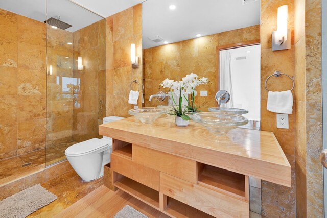 bathroom featuring vanity, toilet, tile walls, and a tile shower