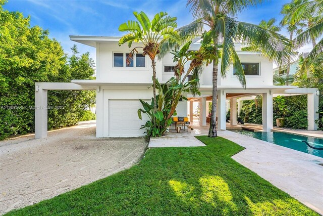 view of front of home featuring an outdoor pool, stucco siding, a patio, and a front lawn