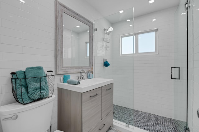 bathroom with vanity, a shower with shower door, tile walls, and toilet