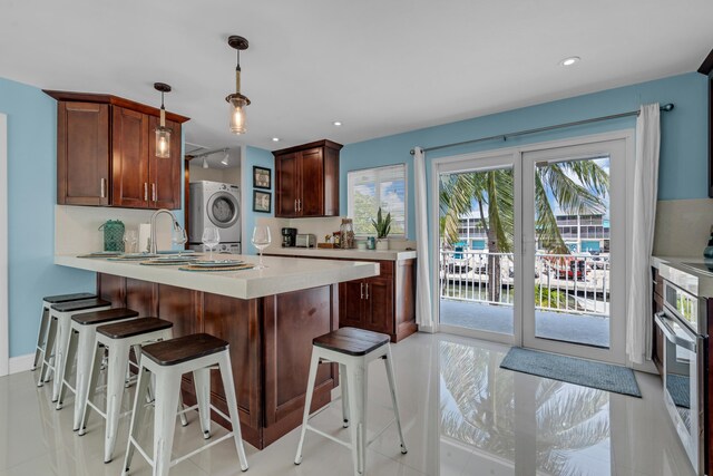 kitchen with hanging light fixtures, sink, a healthy amount of sunlight, and stacked washer / dryer