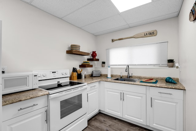 kitchen with dark wood-type flooring, sink, white cabinetry, white appliances, and a drop ceiling