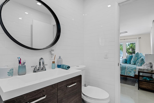 bathroom featuring tile walls, vanity, and toilet