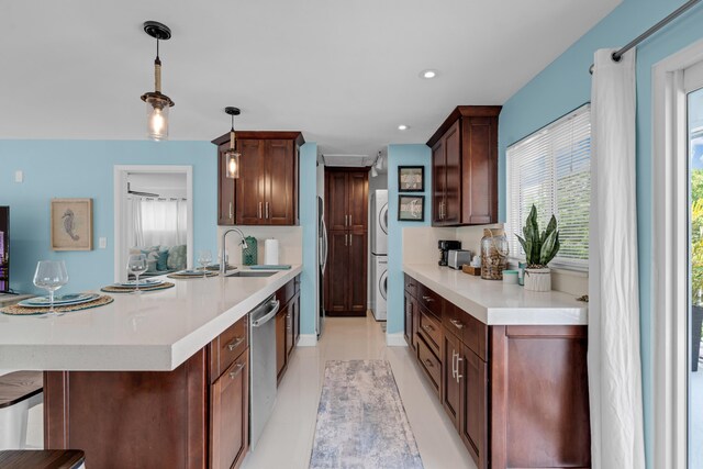 kitchen featuring a kitchen bar, sink, decorative light fixtures, dishwasher, and stacked washing maching and dryer