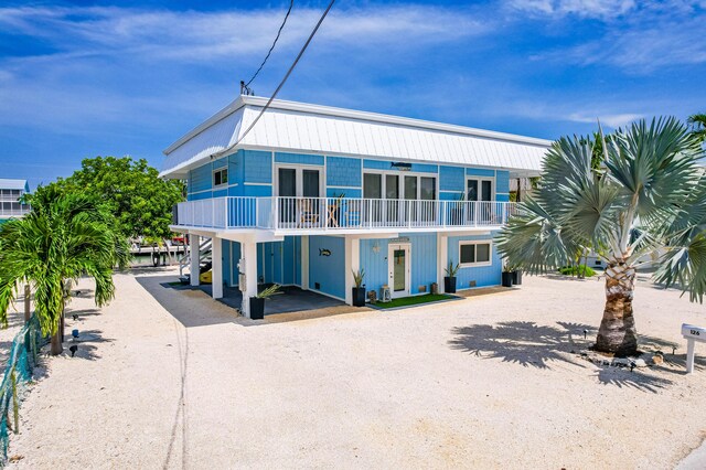 view of front of house featuring a carport, a balcony, and french doors