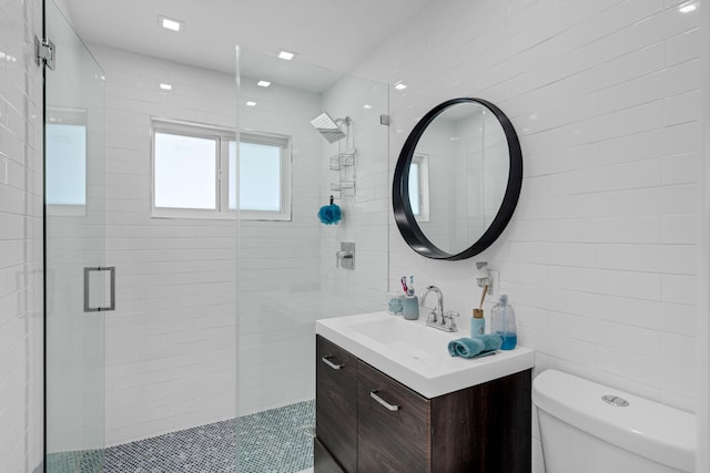 bathroom featuring walk in shower, vanity, toilet, and tile walls