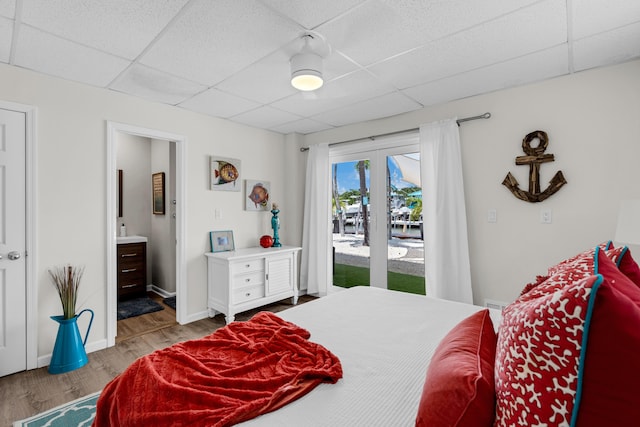 bedroom featuring ensuite bathroom, a paneled ceiling, access to outside, and light hardwood / wood-style floors