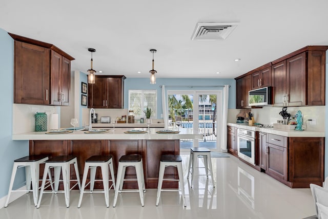 kitchen featuring appliances with stainless steel finishes, decorative light fixtures, a kitchen breakfast bar, and light tile patterned floors