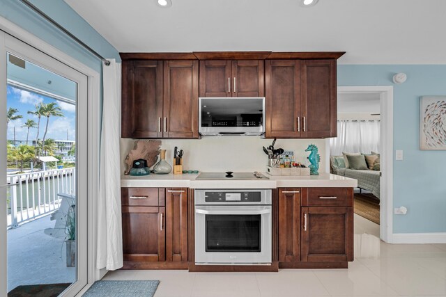 kitchen featuring dark brown cabinets, light tile patterned flooring, stainless steel appliances, and a water view