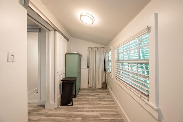 hallway with lofted ceiling and light wood-type flooring