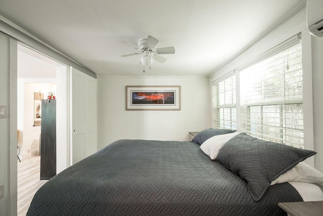 bedroom featuring a wall mounted air conditioner, light hardwood / wood-style flooring, ornamental molding, and ceiling fan