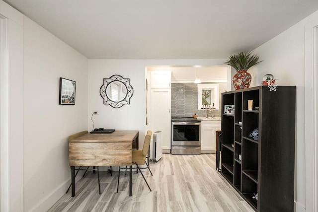 kitchen featuring tasteful backsplash, white cabinets, light hardwood / wood-style floors, and stainless steel range with electric stovetop